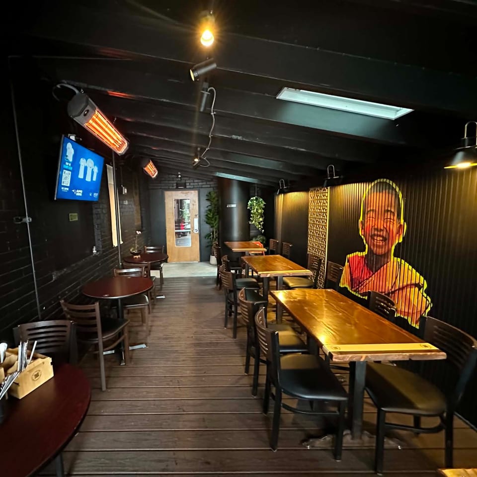 Cozy restaurant dining area with dark decor, wooden tables, and a vibrant mural of a smiling child.